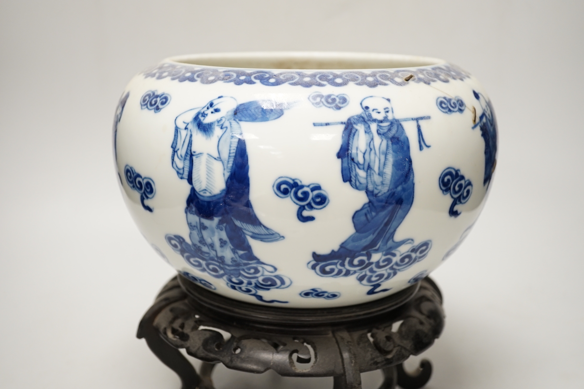 A 19th century Chinese blue and white ‘eight immortals’ alms bowl, apocryphal Qianlong seal mark, 25cm diameter (a.f.), wood stand